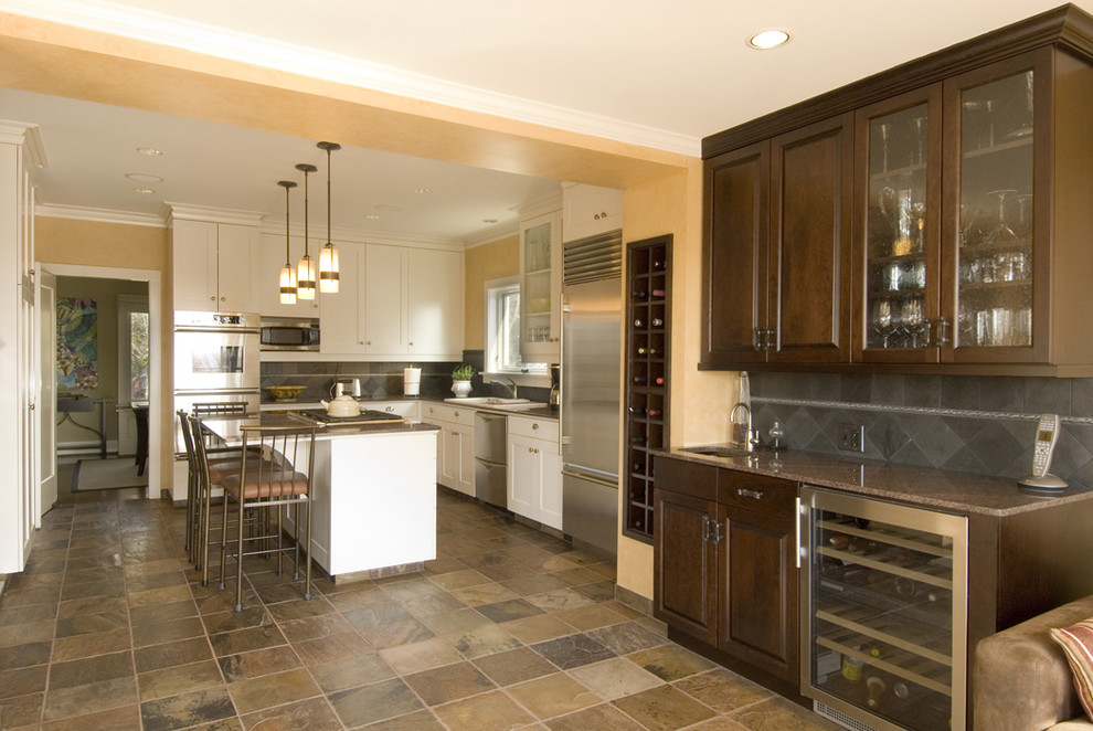 Cette image montre une cuisine traditionnelle en L avec un placard avec porte à panneau encastré, des portes de placard blanches, une crédence grise et un électroménager en acier inoxydable.