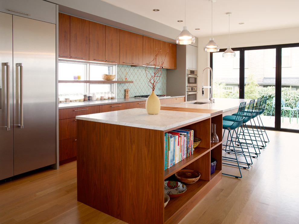 Modern inredning av ett mellanstort kök, med en undermonterad diskho, släta luckor, skåp i mörkt trä, marmorbänkskiva, blått stänkskydd, stänkskydd i glaskakel, rostfria vitvaror, ljust trägolv och en köksö