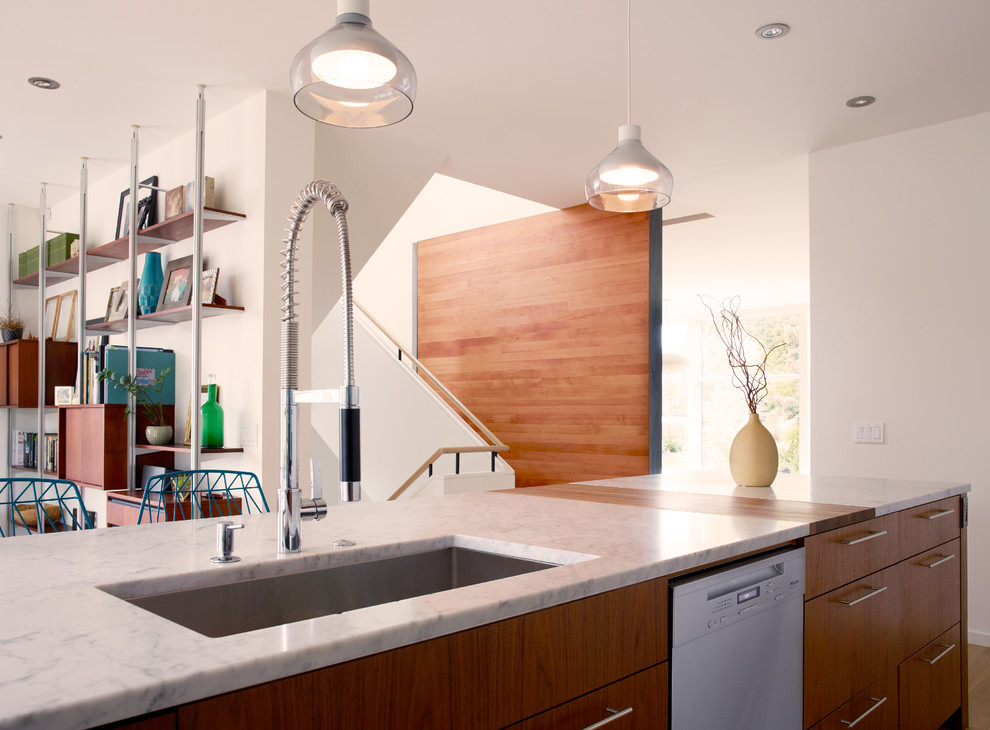 Immagine di una cucina moderna di medie dimensioni con lavello sottopiano, ante lisce, ante in legno bruno, top in marmo, elettrodomestici in acciaio inossidabile, parquet chiaro, pavimento marrone e top bianco