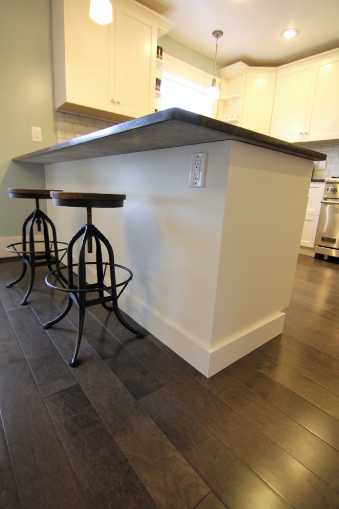Small arts and crafts u-shaped medium tone wood floor enclosed kitchen photo in Seattle with an undermount sink, shaker cabinets, white cabinets, quartzite countertops, white backsplash, subway tile backsplash, stainless steel appliances and a peninsula