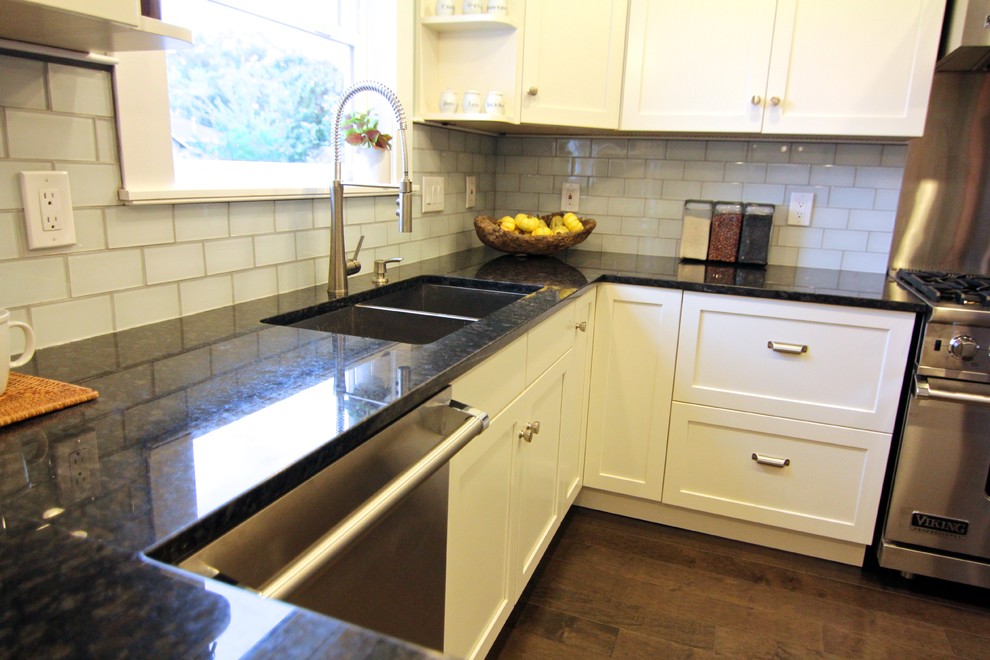 Example of a small arts and crafts u-shaped medium tone wood floor enclosed kitchen design in Seattle with an undermount sink, shaker cabinets, white cabinets, quartzite countertops, white backsplash, subway tile backsplash, stainless steel appliances and a peninsula