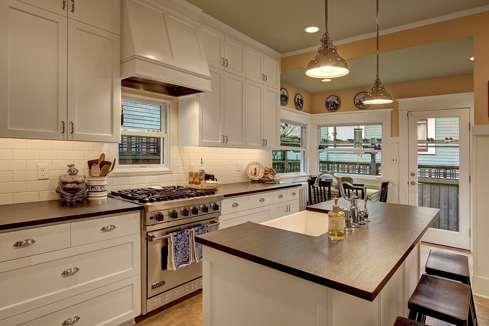 Design ideas for a large classic l-shaped enclosed kitchen in Seattle with a belfast sink, shaker cabinets, white cabinets, engineered stone countertops, white splashback, metro tiled splashback, stainless steel appliances and an island.
