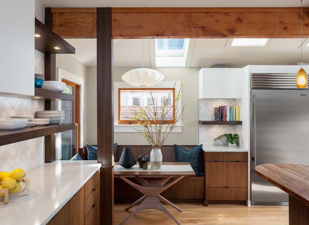 Inspiration for a mid-sized mid-century modern l-shaped medium tone wood floor eat-in kitchen remodel in Seattle with an undermount sink, medium tone wood cabinets, quartz countertops, white backsplash, stone tile backsplash and stainless steel appliances