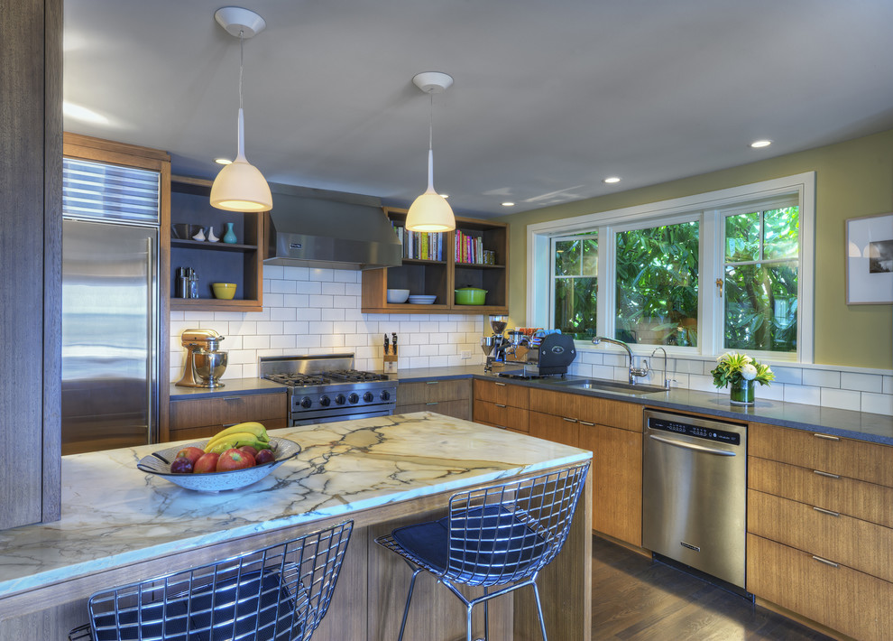シアトルにあるミッドセンチュリースタイルのおしゃれなキッチン (アンダーカウンターシンク、フラットパネル扉のキャビネット、中間色木目調キャビネット、白いキッチンパネル、サブウェイタイルのキッチンパネル、シルバーの調理設備) の写真