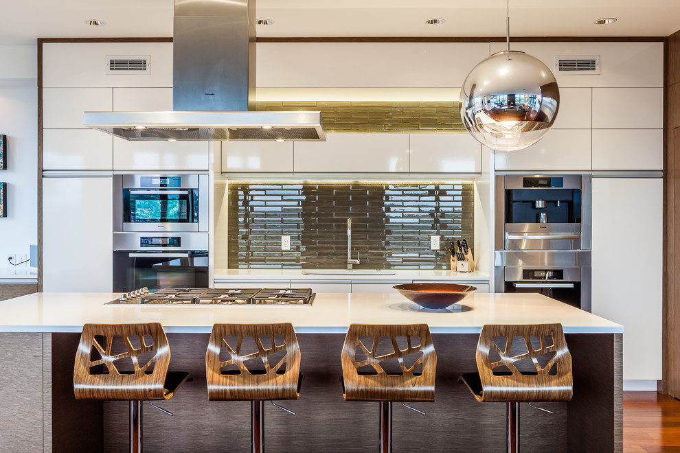 Moderne Küche mit Unterbauwaschbecken, flächenbündigen Schrankfronten, weißen Schränken, Küchenrückwand in Grün, Küchengeräten aus Edelstahl, braunem Holzboden und Kücheninsel in Seattle
