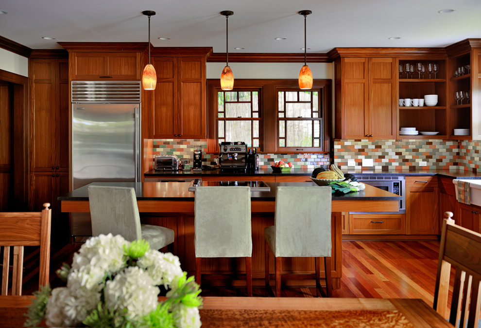 Modelo de cocina comedor de estilo americano con fregadero sobremueble, armarios estilo shaker, puertas de armario de madera oscura, salpicadero multicolor, salpicadero con mosaicos de azulejos, electrodomésticos de acero inoxidable, suelo de madera en tonos medios y una isla