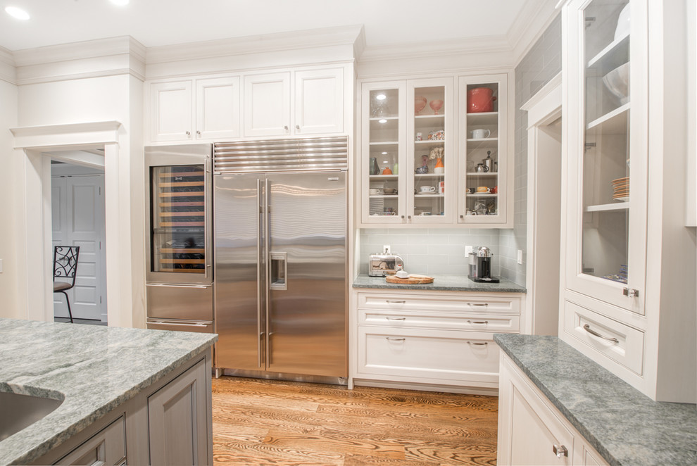 Example of a large classic u-shaped medium tone wood floor enclosed kitchen design in Seattle with an undermount sink, beaded inset cabinets, white cabinets, granite countertops, green backsplash, glass tile backsplash, stainless steel appliances and an island