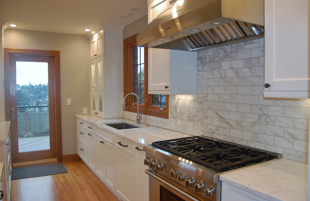 This is an example of a medium sized classic galley enclosed kitchen in Seattle with a single-bowl sink, shaker cabinets, white cabinets, marble worktops, grey splashback, marble splashback, stainless steel appliances, medium hardwood flooring and no island.
