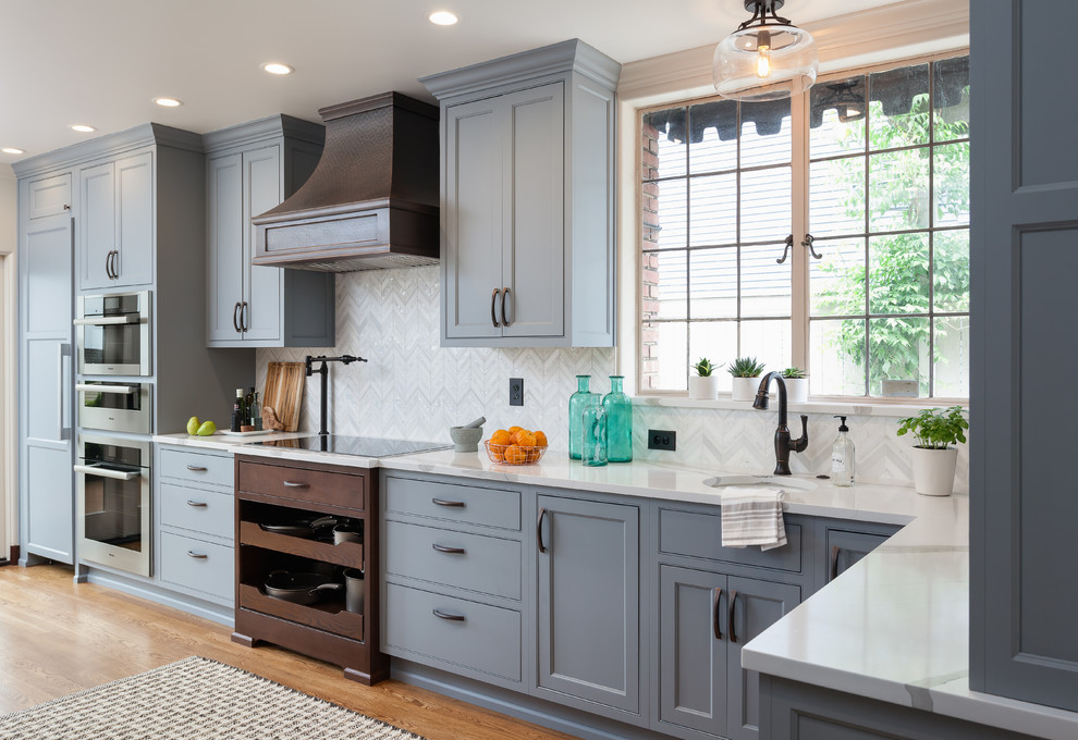 Large traditional kitchen in Seattle with a submerged sink, beaded cabinets, blue cabinets, engineered stone countertops, white splashback, mosaic tiled splashback, integrated appliances, medium hardwood flooring and brown floors.