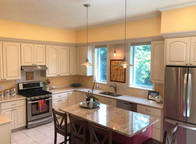 Klassisk inredning av ett mycket stort beige beige kök, med en dubbel diskho, luckor med upphöjd panel, vita skåp, granitbänkskiva, vitt stänkskydd, stänkskydd i porslinskakel, rostfria vitvaror, ljust trägolv, en köksö och vitt golv