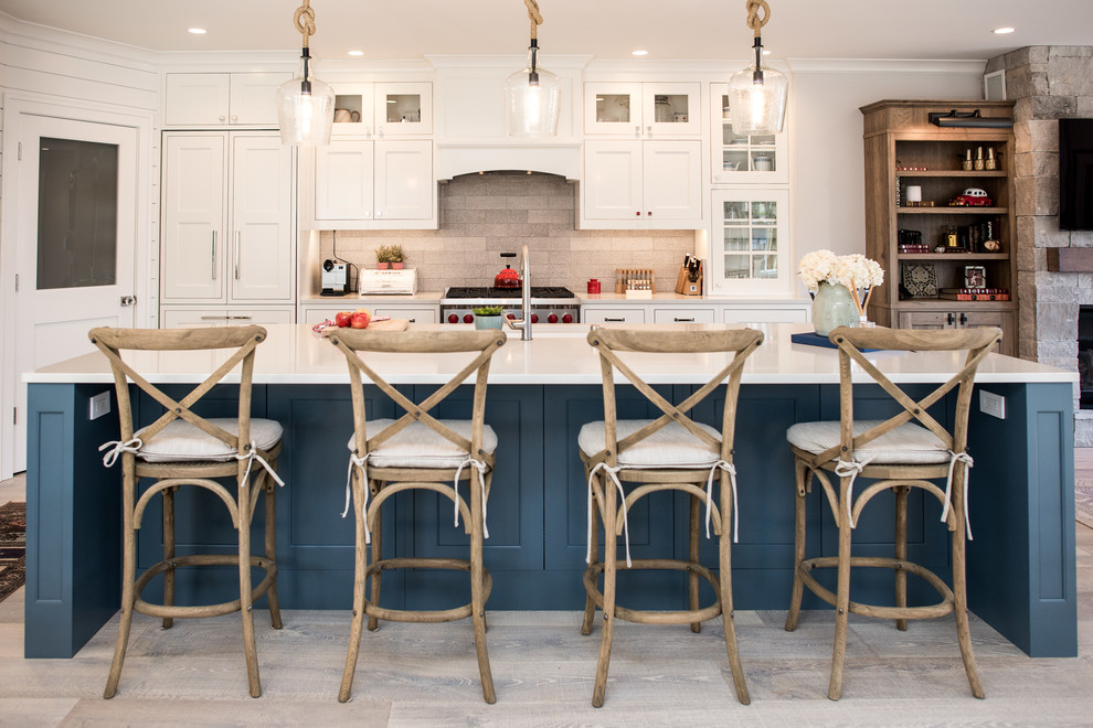 Beach style galley gray floor kitchen photo in Seattle with an undermount sink, shaker cabinets, white cabinets, gray backsplash, stainless steel appliances, an island and white countertops
