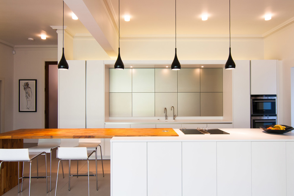 На фото: параллельная кухня в современном стиле с плоскими фасадами и белыми фасадами с