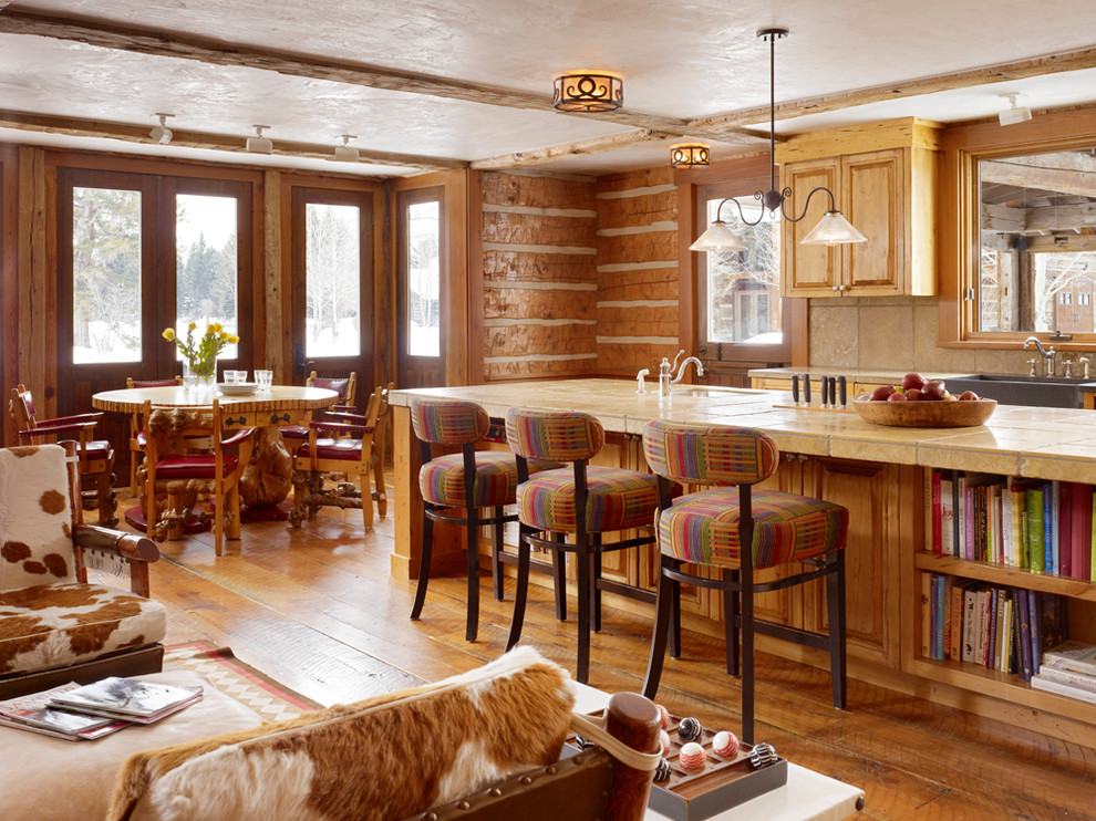 На фото: кухня в стиле рустика с обеденным столом, фасадами с выступающей филенкой и фасадами цвета дерева среднего тона с