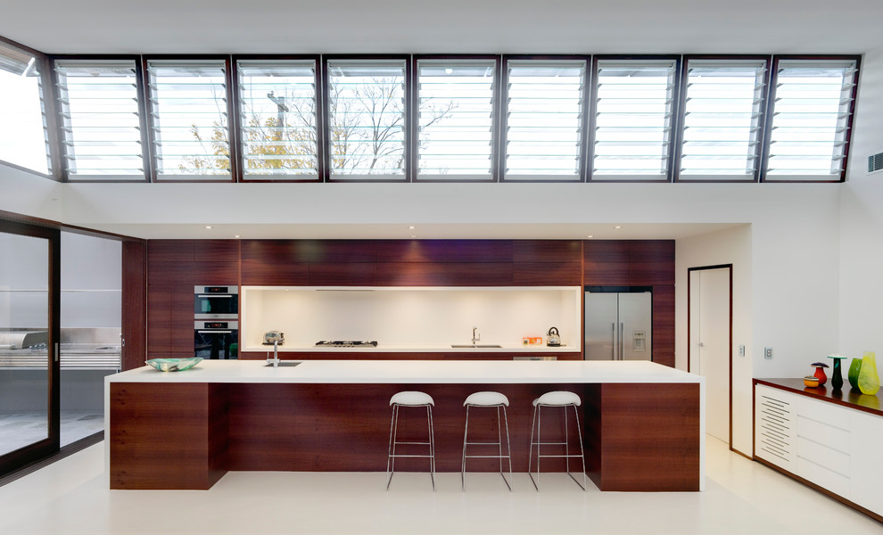 Example of a trendy single-wall kitchen design in Sydney with flat-panel cabinets, dark wood cabinets, white backsplash and stainless steel appliances