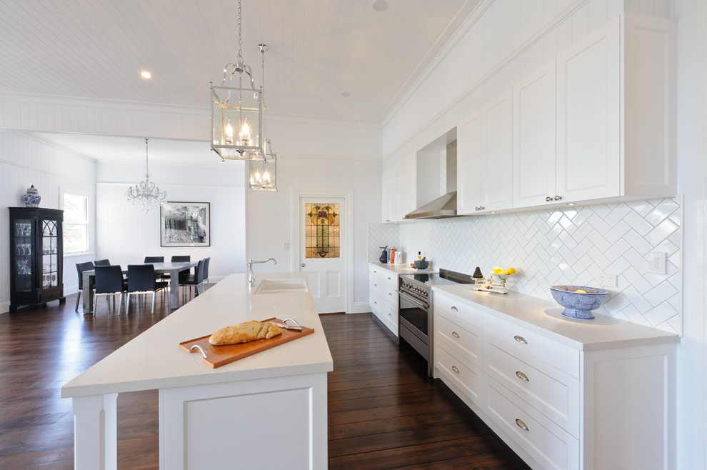 Design ideas for a large classic single-wall open plan kitchen in Brisbane with shaker cabinets, white cabinets, white splashback, porcelain splashback, dark hardwood flooring and an island.