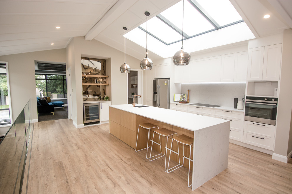 Inspiration for a medium sized modern single-wall kitchen pantry in Hamilton with a built-in sink, beaded cabinets, white cabinets, white splashback, stainless steel appliances, medium hardwood flooring, an island, brown floors and white worktops.