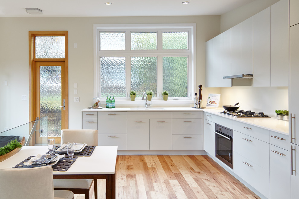Small minimalist l-shaped light wood floor open concept kitchen photo in Vancouver with an undermount sink, flat-panel cabinets, yellow cabinets, quartzite countertops, white backsplash, ceramic backsplash and paneled appliances
