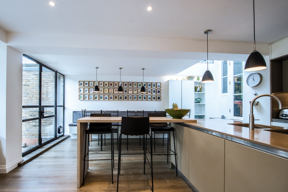 Moderne Küche mit flächenbündigen Schrankfronten, braunen Schränken und Kücheninsel in London