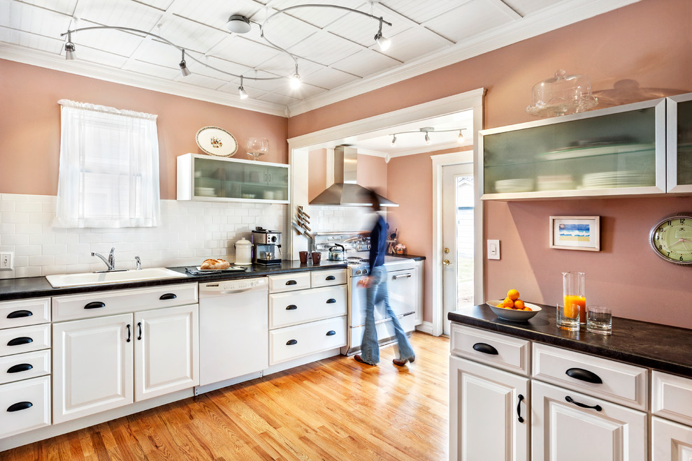 Exempel på ett klassiskt kök, med en nedsänkt diskho, luckor med upphöjd panel, vita skåp, laminatbänkskiva, vitt stänkskydd, stänkskydd i tunnelbanekakel och vita vitvaror