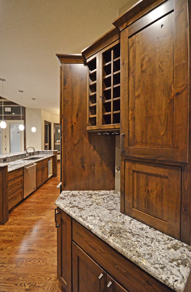 デンバーにある中くらいなラスティックスタイルのおしゃれなキッチン (フラットパネル扉のキャビネット、中間色木目調キャビネット、シルバーの調理設備) の写真