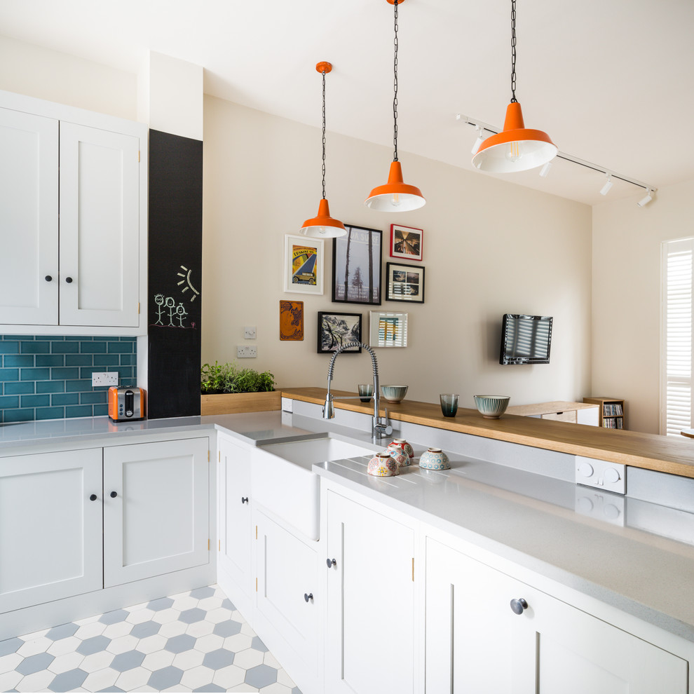 Exempel på ett litet modernt kök, med en rustik diskho, skåp i shakerstil, vita skåp, bänkskiva i kvarts, blått stänkskydd, stänkskydd i tunnelbanekakel, rostfria vitvaror, klinkergolv i keramik, en halv köksö och flerfärgat golv