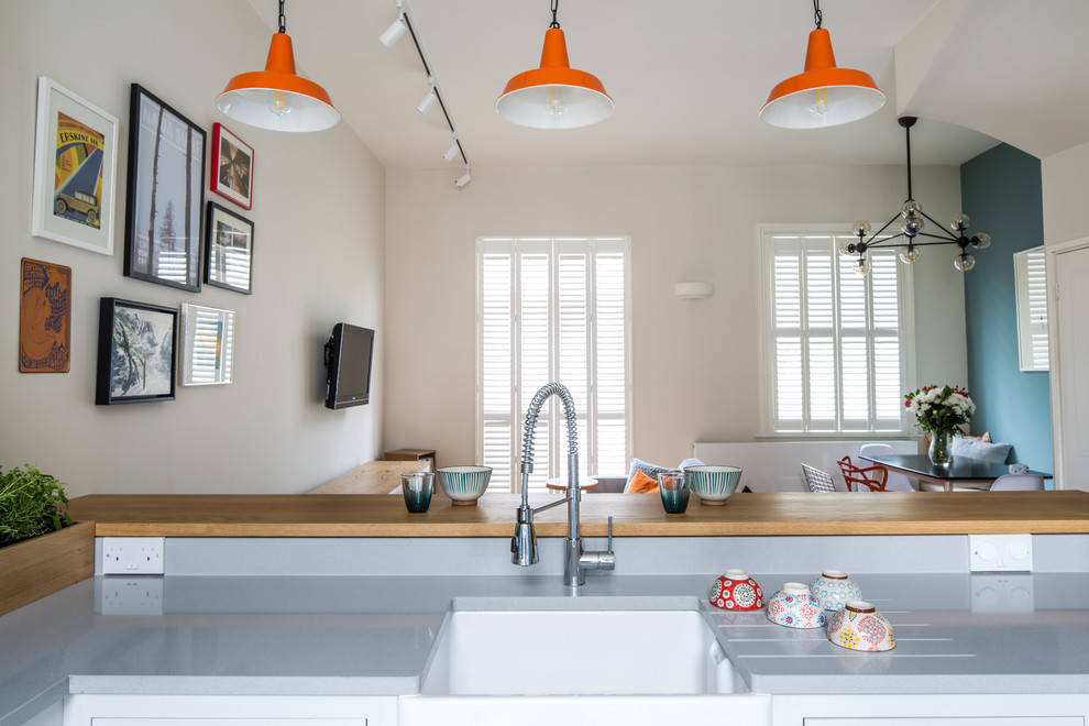 Inspiration for a small contemporary l-shaped open plan kitchen in London with a belfast sink, shaker cabinets, white cabinets, engineered stone countertops, blue splashback, metro tiled splashback, stainless steel appliances, ceramic flooring, a breakfast bar and multi-coloured floors.