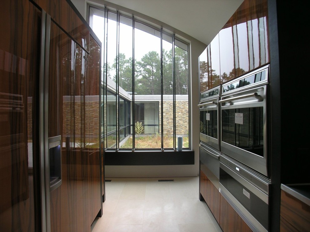 Große Moderne Wohnküche mit integriertem Waschbecken, Edelstahl-Arbeitsplatte, schwarzen Elektrogeräten und weißem Boden in Sonstige