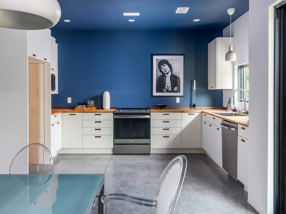 This is an example of a medium sized urban l-shaped open plan kitchen in Nashville with a submerged sink, flat-panel cabinets, white cabinets, wood worktops, blue splashback, stainless steel appliances, concrete flooring, no island and grey floors.