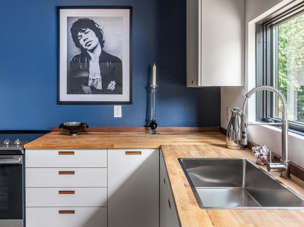 This is an example of a medium sized industrial l-shaped open plan kitchen in Nashville with a submerged sink, flat-panel cabinets, white cabinets, wood worktops, blue splashback, stainless steel appliances, concrete flooring, no island and grey floors.