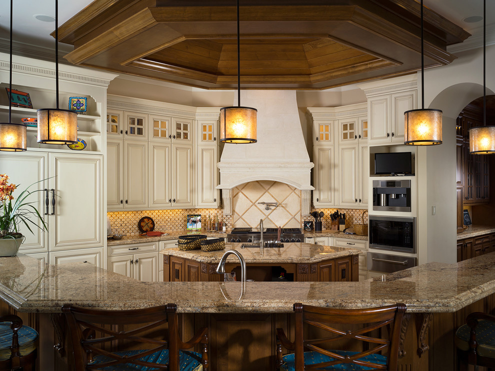 Foto di un cucina con isola centrale tropicale con ante in legno chiaro, top in granito e elettrodomestici in acciaio inossidabile