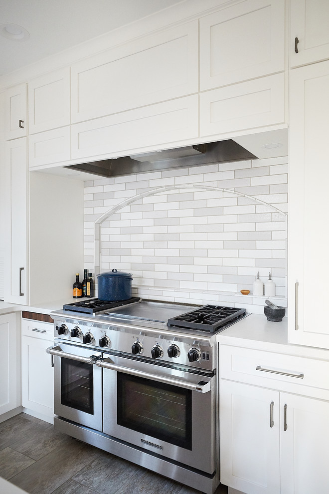 Large trendy u-shaped ceramic tile and gray floor eat-in kitchen photo in Minneapolis with a farmhouse sink, shaker cabinets, white cabinets, quartz countertops, gray backsplash, subway tile backsplash, stainless steel appliances, an island and white countertops