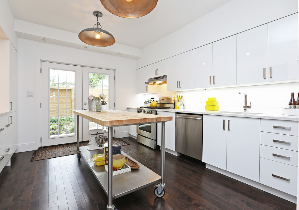 Example of a mid-sized transitional galley dark wood floor and brown floor enclosed kitchen design in Toronto with an undermount sink, flat-panel cabinets, white cabinets, quartzite countertops, white backsplash, cement tile backsplash, stainless steel appliances, an island and white countertops