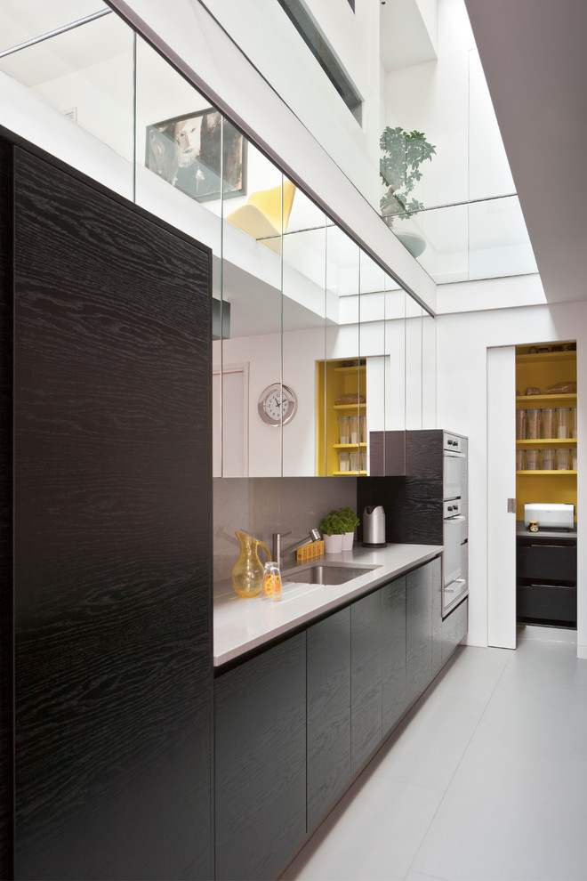 Photo of a contemporary kitchen in London with a submerged sink, flat-panel cabinets, black cabinets and stainless steel appliances.