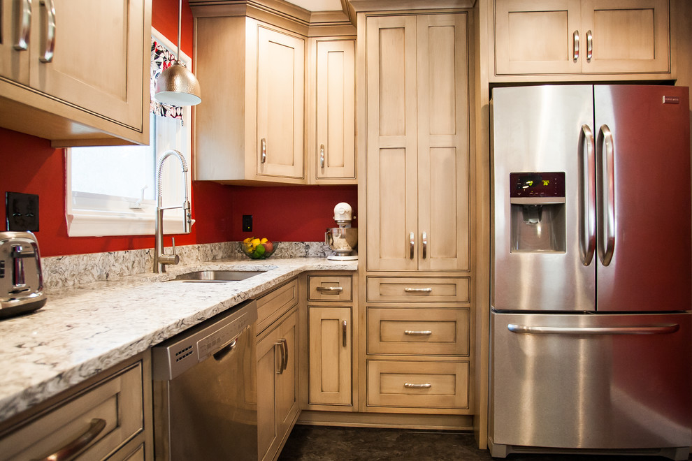 This is an example of a traditional u-shaped enclosed kitchen in Baltimore with a submerged sink, shaker cabinets, light wood cabinets, granite worktops, stainless steel appliances, vinyl flooring and an island.