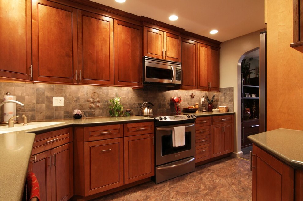 Modern inredning av ett kök, med en nedsänkt diskho, luckor med profilerade fronter, skåp i mellenmörkt trä, laminatbänkskiva, grått stänkskydd, stänkskydd i keramik, rostfria vitvaror, linoleumgolv och en köksö