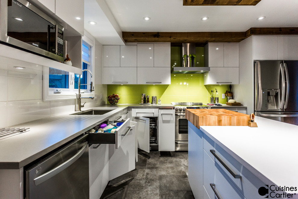 Bild på ett stort funkis kök, med en undermonterad diskho, släta luckor, vita skåp, bänkskiva i kvartsit, grönt stänkskydd, stänkskydd i keramik, rostfria vitvaror, betonggolv och en köksö