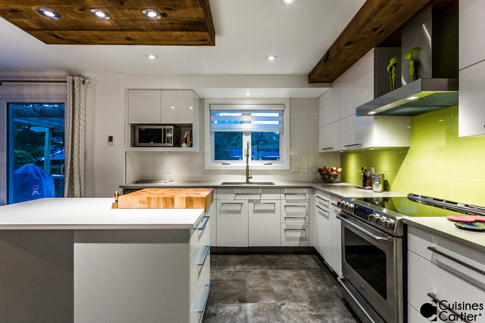 Modern inredning av ett stort kök, med en undermonterad diskho, släta luckor, vita skåp, bänkskiva i kvartsit, grönt stänkskydd, stänkskydd i keramik, rostfria vitvaror, betonggolv och en köksö