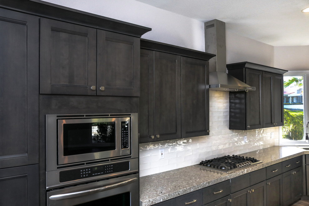Exempel på ett stort modernt grå grått kök, med en undermonterad diskho, luckor med infälld panel, skåp i mörkt trä, granitbänkskiva, vitt stänkskydd, stänkskydd i keramik, rostfria vitvaror, en köksö, brunt golv och klinkergolv i porslin
