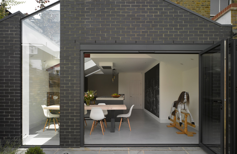 Einzeilige, Große Moderne Wohnküche mit flächenbündigen Schrankfronten, schwarzen Schränken, Betonarbeitsplatte, Kücheninsel, grauem Boden und beiger Arbeitsplatte in London