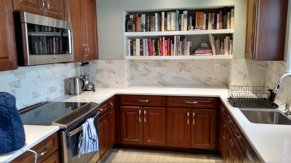 Klassisk inredning av ett litet kök, med en undermonterad diskho, luckor med upphöjd panel, skåp i mellenmörkt trä, bänkskiva i kvarts, flerfärgad stänkskydd, stänkskydd i porslinskakel, rostfria vitvaror och klinkergolv i porslin