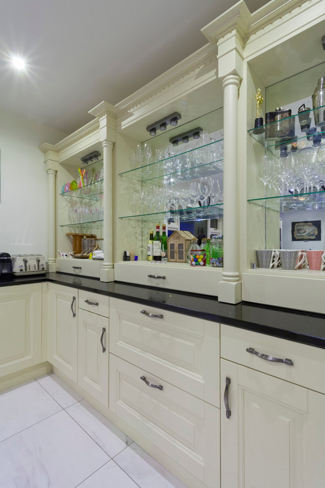 Example of a mid-sized ornate l-shaped eat-in kitchen design in Dublin with an undermount sink, raised-panel cabinets, quartzite countertops and an island