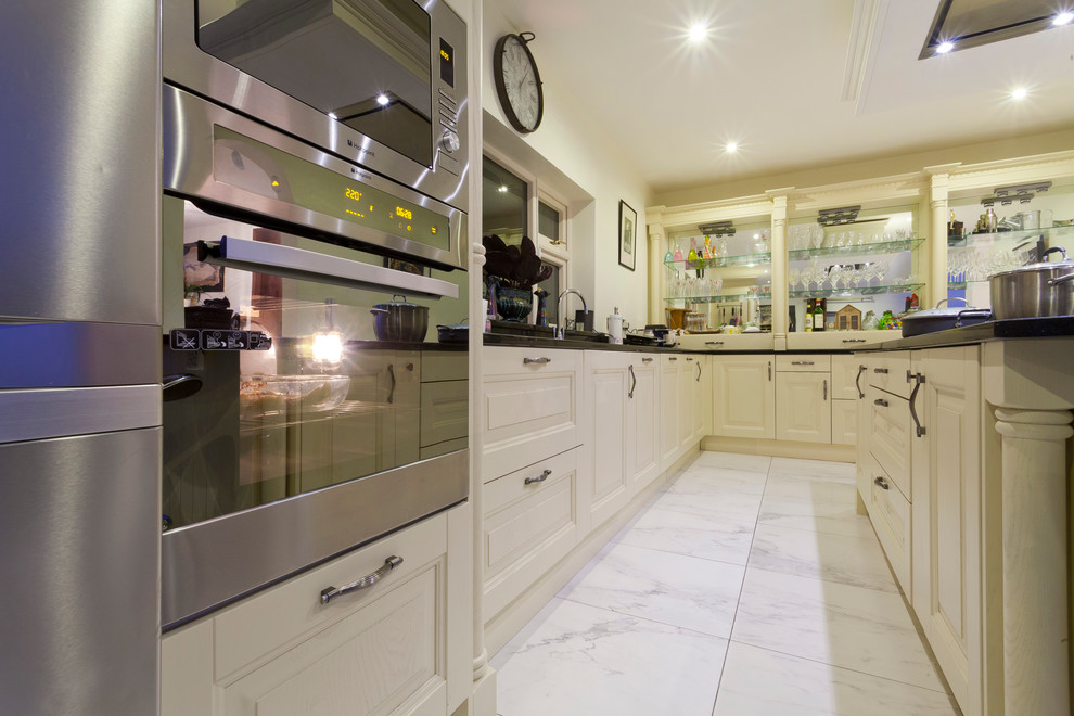 This is an example of a medium sized victorian l-shaped kitchen/diner in Dublin with a submerged sink, raised-panel cabinets, quartz worktops and an island.