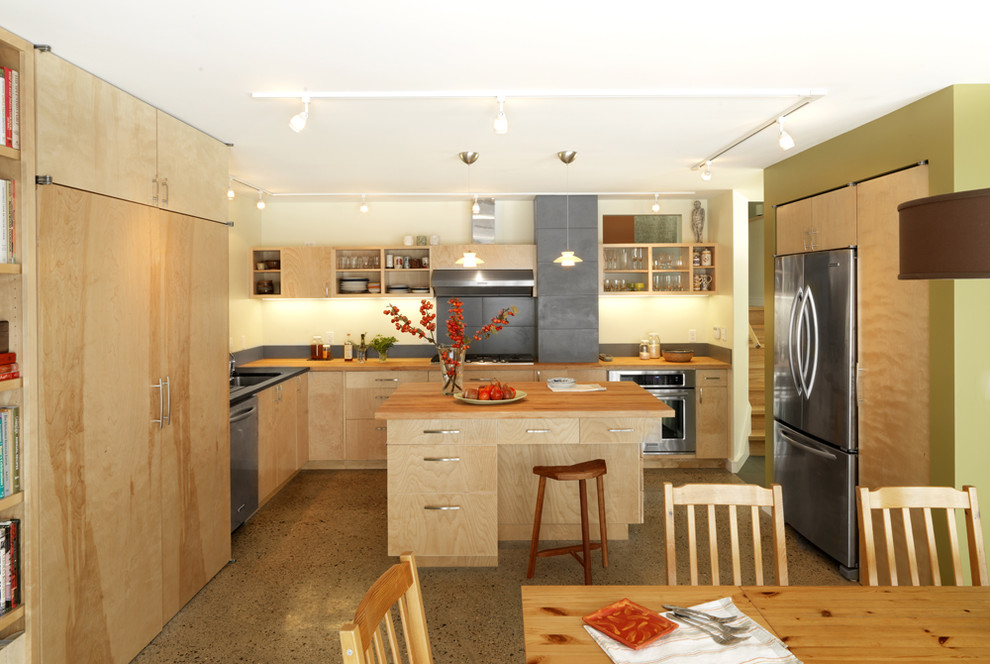 Идея дизайна: кухня в современном стиле с плоскими фасадами, обеденным столом, техникой из нержавеющей стали и деревянной столешницей
