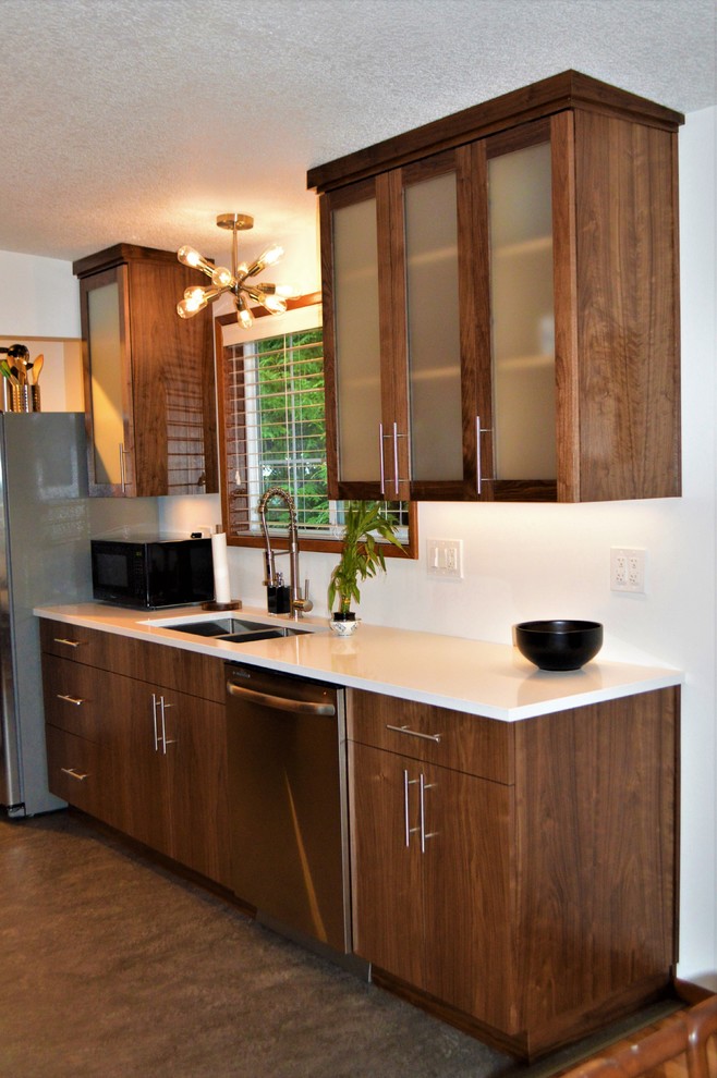 Cette photo montre une cuisine ouverte parallèle rétro en bois brun de taille moyenne avec un évier 1 bac, un placard à porte plane, un plan de travail en surface solide, un électroménager en acier inoxydable, un sol en linoléum et un sol gris.