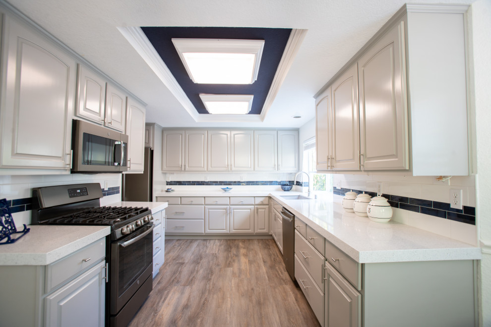 Small transitional u-shaped brown floor eat-in kitchen photo in San Francisco with an undermount sink, raised-panel cabinets, beige cabinets, white backsplash, subway tile backsplash, stainless steel appliances, no island and white countertops