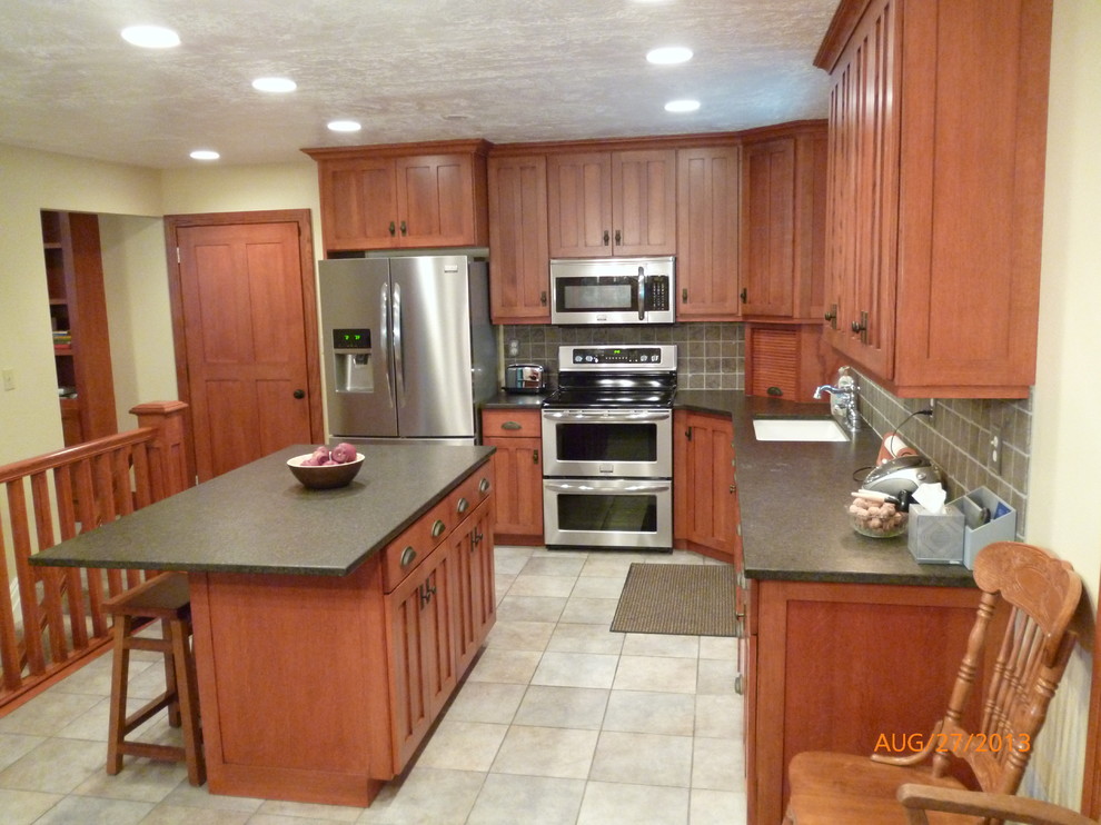 Bild på ett stort amerikanskt kök, med en undermonterad diskho, släta luckor, skåp i ljust trä, granitbänkskiva, grått stänkskydd, stänkskydd i stenkakel, rostfria vitvaror, klinkergolv i porslin och en köksö