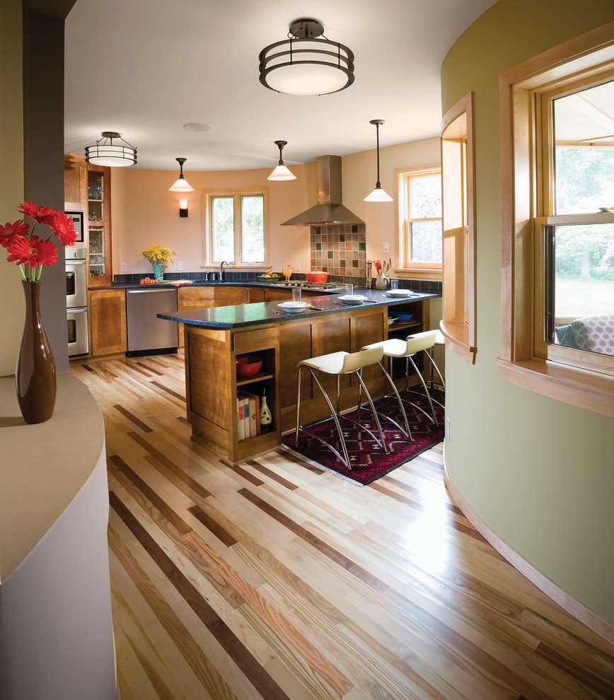 Cette photo montre une cuisine tendance en U avec une crédence noire, un électroménager en acier inoxydable et un sol en bois brun.