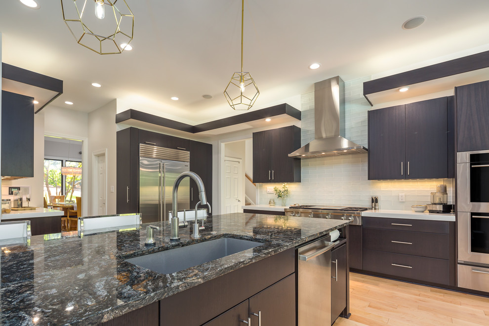 Eat-in kitchen - large contemporary single-wall light wood floor eat-in kitchen idea in Raleigh with an undermount sink, flat-panel cabinets, dark wood cabinets, quartz countertops, white backsplash, glass tile backsplash, stainless steel appliances, an island and white countertops