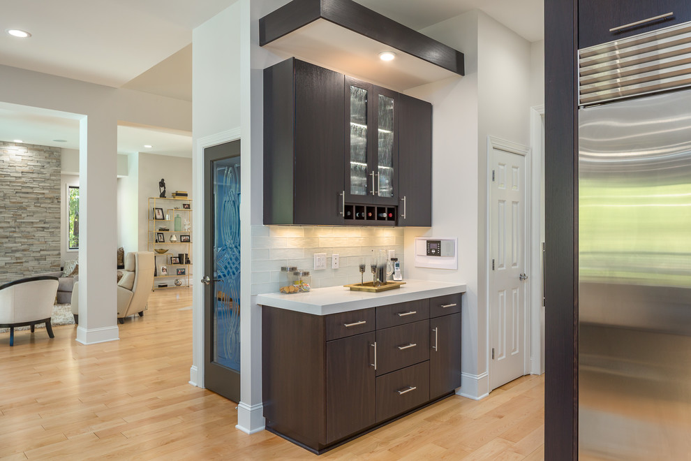 Example of a large trendy single-wall light wood floor eat-in kitchen design in Raleigh with an undermount sink, flat-panel cabinets, dark wood cabinets, quartz countertops, white backsplash, glass tile backsplash, stainless steel appliances, an island and white countertops