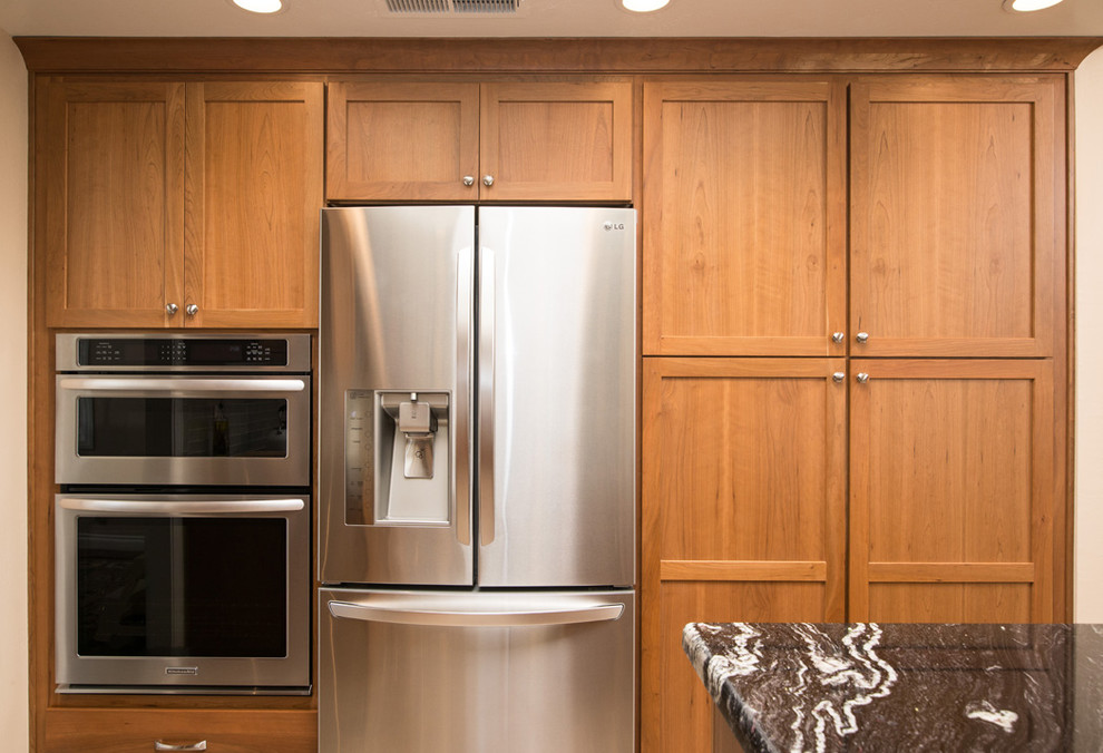 Example of a large trendy l-shaped eat-in kitchen design in San Diego with a drop-in sink, light wood cabinets, granite countertops, white backsplash, glass tile backsplash, stainless steel appliances and an island